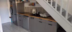 a kitchen with white cabinets and a sink under a staircase at Maison au pin in Narbonne-Plage +4 photos