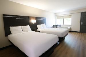 two beds in a hotel room with white sheets at Paragon Inn Hillsboro in Hillsboro
