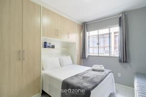 a small bedroom with a bed and a window at Aptos em prédio a 500m da Praia de Canasvieiras - GALs in Florianópolis