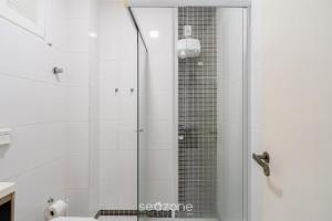 a shower with a glass door in a bathroom at Aptos em prédio a 500m da Praia de Canasvieiras - GALs in Florianópolis +17 photos