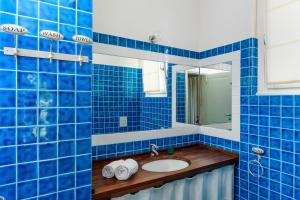 een blauw betegelde badkamer met een wastafel en een spiegel bij Li Conchi 33 in Cala Sinzias +19 foto's