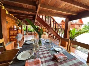a table with plates and wine glasses on a porch at Wang Namthip Hotel in Muang Fuang