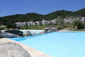 een groot zwembad met rotsen en huizen bij Li Conchi 33 in Cala Sinzias