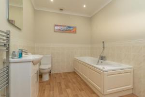 a bathroom with a sink and a tub and a toilet at Ty-Ffynnon in Penmaen-mawr +24 photos