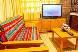 a living room with a tv and a couch and a table at Casa del Huesped in Otavalo +9 photos