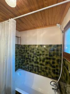 a bathroom with a tub and a green tiled wall at South-facing Chalet With Views in Le Villard-Late