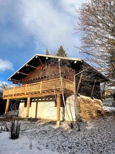 a house with a wooden deck in the snow at South-facing Chalet With Views in Le Villard-Late