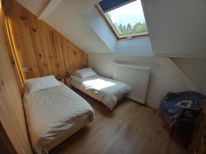 a attic bedroom with two beds and a window at Gîte Les Ebeteux in Fraize