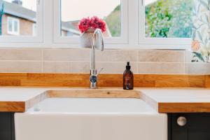 eine Küchenspüle mit einem Wasserhahn neben einem Fenster in der Unterkunft Wisteria Cottage 3 Bed Garden & Free Parking in Kenilworth + 22 Fotos