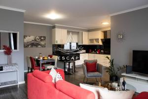a living room with a red couch and a kitchen at Cottage Bela Vista by Escape to Madeira in Cedros