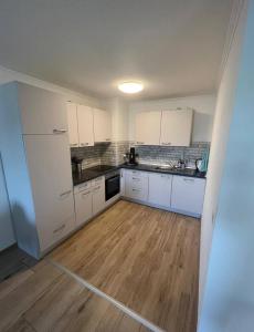 a kitchen with white cabinets and a wooden floor at Apartment O&V 2 in Waldshut-Tiengen