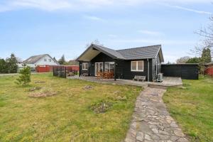 a small black house on a grass field at Snug In Snogebæk A Modern Cozy Summer House in Neksø