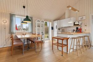 a kitchen and dining room with a table and chairs at Snug In Snogebæk A Modern Cozy Summer House in Neksø +18 photos