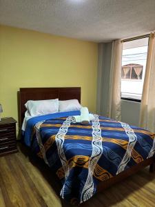 ein Schlafzimmer mit einem Bett mit einer blau-goldenen Decke in der Unterkunft Jacquelins house in Baños + 3 Fotos