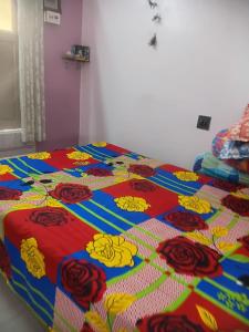 a bed with a colorful comforter with roses on it at Urban Nest Homestay 3BHK full furnished in Mullāhjor