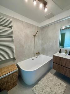 a bathroom with a tub and a tv on the wall at HelloWine Apartman in Eger