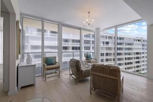 een woonkamer met een tafel en stoelen en grote ramen bij Chic Three-Bedroom Oceanfront Apartment with Stunning Views in South Palm Beach