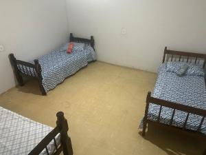 two twin beds in a room with a tile floor at Hotel Automatiza no Centro da Cidade in Uberaba
