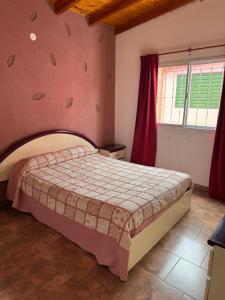- une chambre avec un grand lit et un mur rose dans l'établissement Lodemarta, à Villa Carlos Paz 3 autres photos