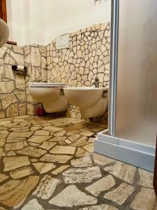 a stone bathroom with two toilets and a shower at Affittacamere La Grotta Magica in Venagrande +2 photos