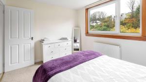 a white bedroom with a bed and a window at Sea The View in Rothesay