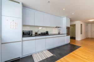 a kitchen with white cabinets and a wooden floor at Swiss Suites - Stusslingen in Lostorf