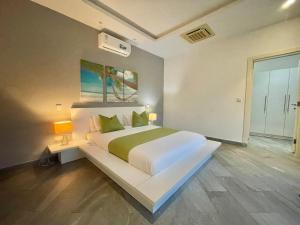 ディアニ・ビーチにあるAmber Villas Dianiの緑の枕が付いた大きな白いベッドのある寝室