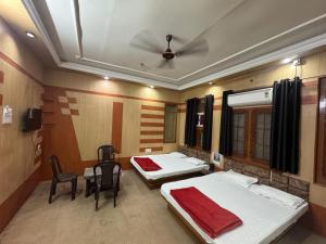 a room with two beds and a table and chairs at Perfect Homestay Ujjain in Ujjain