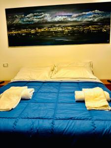 a bed with blue sheets and a painting on the wall at Affittacamere La Grotta Magica in Venagrande