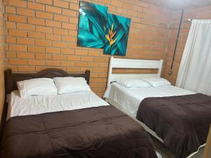 two beds in a room with a brick wall at Sito São Joaquim in Itaquá