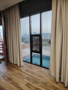 a room with a large window with a swimming pool at كهف الريف Reef Cave in Al Ḩamrāʼ
