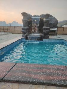 a swimming pool with a fountain in the middle at كهف الريف Reef Cave in Al Ḩamrāʼ +3 photos