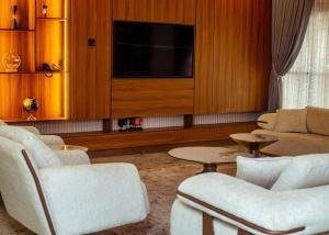 a living room with white chairs and a flat screen tv at Mthree residence and apartment Ltd in Abuja +9 photos