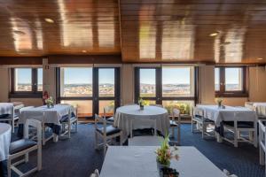 a restaurant with white tables and chairs and windows at Hotel Apartamento Solverde in Espinho