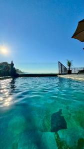 a pool of water with a person sitting under an umbrella at A CASA DI GHJULIA PISCINE CHAUFFEE PROCHE St FLORENT in Vallecalle
