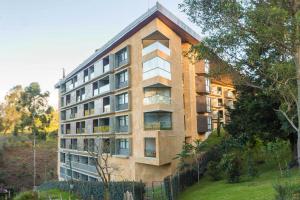a building on a hill next to a field at Apartasuite cercana al aeropuerto internacional MED in San Antonio de Pereira