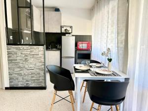 a kitchen with a white table and two black chairs at Large Studio with sleeping area in Carnon-Plage