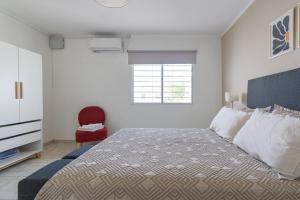 Un dormitorio con una cama y una silla roja. en Hermosa Casa En El Centro de San Rafael, en San Rafael