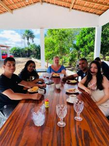 a group of people sitting around a wooden table at Sol Dos Lençois Pousada in Barreirinhas