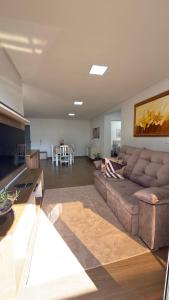 un soggiorno con un divano marrone e un tavolo di Apto Flor Três Marias-2 Quartos- Apto todo climatizado- Moderno, confortável, à 150m do Parque Termal a Piratuba