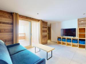 a living room with a blue couch and a tv at Chalet 5* avec spa, sauna et jacuzzi pour 15 pers., accès pistes - FR-1-267-310 in Villarembert