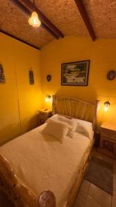 1 dormitorio con cama de madera y paredes amarillas en Villa Josefina, en Santiago Sacatepéquez