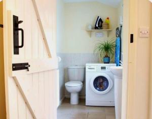a bathroom with a toilet and a washing machine at Nikolaus Cottage Cotswolds in Winchcombe