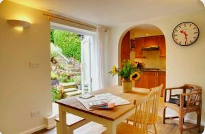 a dining room with a table and a clock on the wall at Nikolaus Cottage Cotswolds in Winchcombe