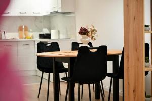 a wooden table with black chairs in a kitchen at Hanan Apartmani in Novi Pazar