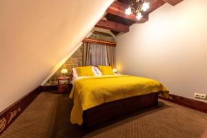 een slaapkamer met een geel bed op een zolder bij Villa Rusalka in Vysoké Tatry