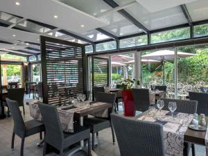a dining room with tables and chairs and windows at ibis Brignoles Provence Verte in Brignoles