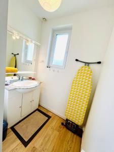 a bathroom with a sink and a yellow and white surfboard at Treasure of Perche-Gouët in a village house! in Arrou