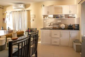 a kitchen with white cabinets and a table and chairs at Lakefront 1 BR Cabin with Lake access & Hammock in Kollam