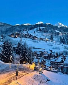 a town in the snow with mountains in the background at Rifugio TEA Dolomiti in Caviola